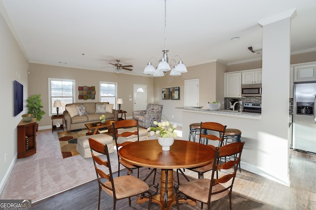 dining area featuring crown molding, dark hardwood / wood-style floors, ceiling fan with notable chandelier, and sink