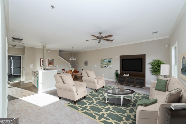 carpeted living room featuring baseboards, visible vents, a ceiling fan, and crown molding