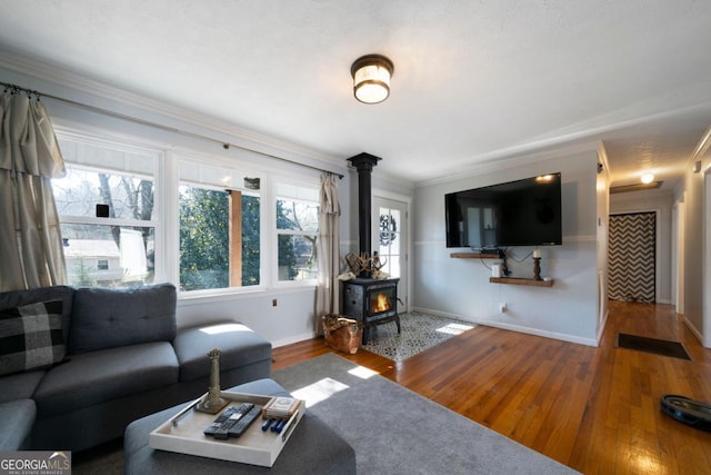 living room with hardwood / wood-style flooring, ornamental molding, and a wood stove