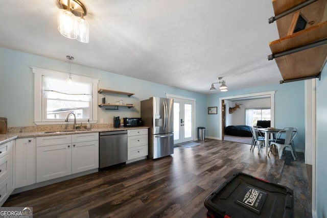 kitchen featuring sink, appliances with stainless steel finishes, white cabinetry, hanging light fixtures, and dark hardwood / wood-style flooring