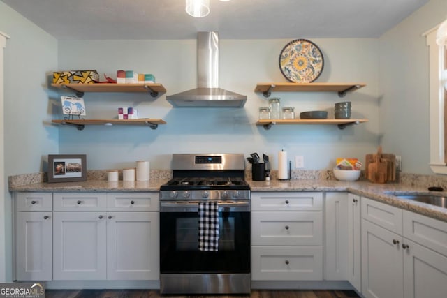 kitchen featuring white cabinetry, light stone counters, gas stove, and wall chimney exhaust hood