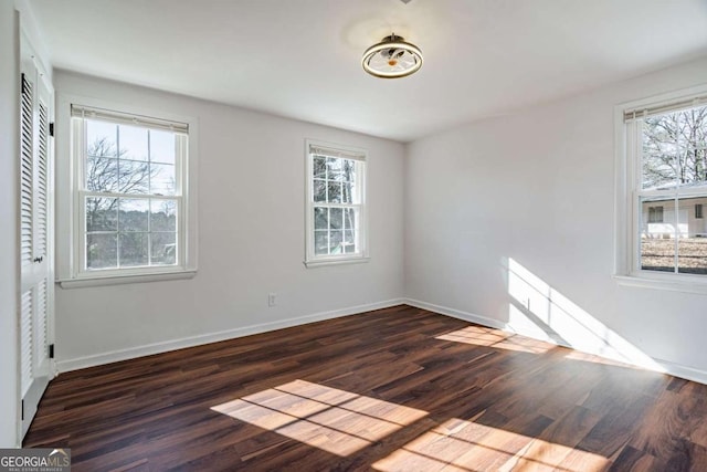 empty room with plenty of natural light and dark hardwood / wood-style floors