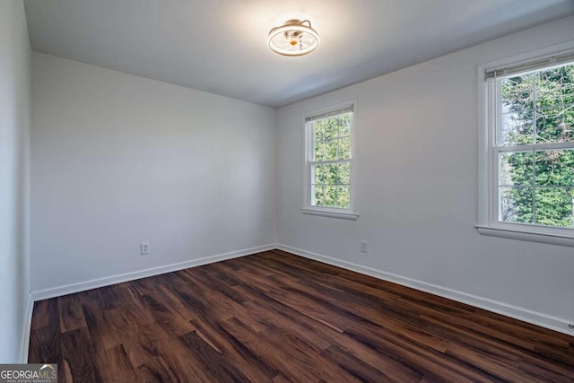 empty room featuring dark wood-type flooring and a healthy amount of sunlight