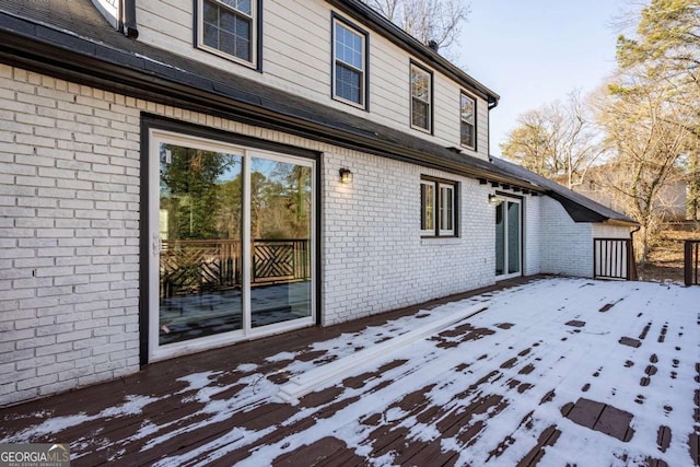 snow covered rear of property with a deck