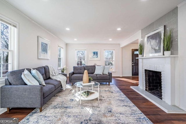 living room with dark hardwood / wood-style flooring, a brick fireplace, and crown molding