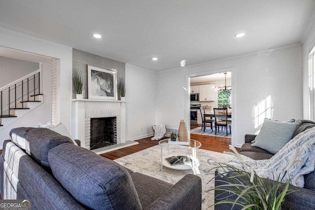 living room with wood-type flooring, a brick fireplace, and crown molding