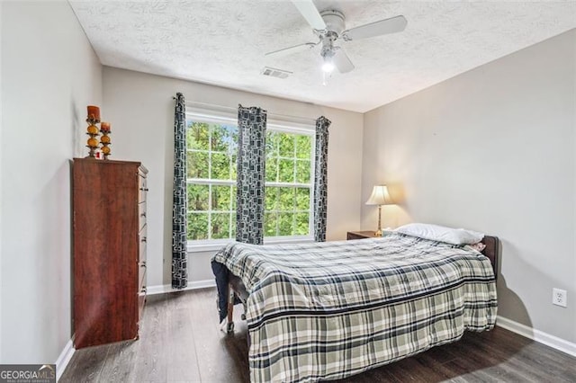 bedroom with dark hardwood / wood-style flooring, a textured ceiling, and ceiling fan