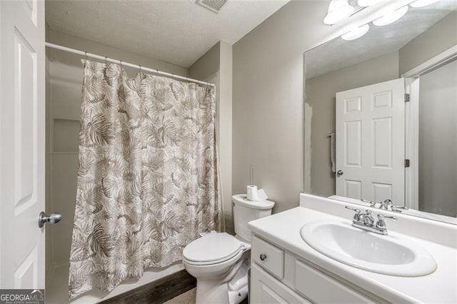 bathroom featuring vanity, toilet, and a textured ceiling