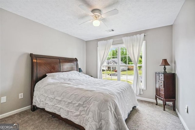 carpeted bedroom with ceiling fan and a textured ceiling