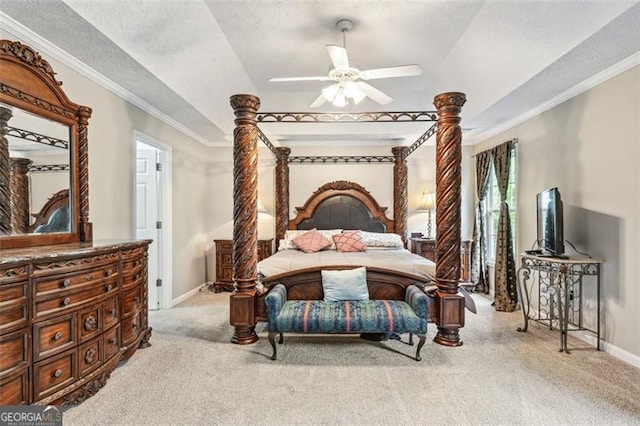 bedroom with ornamental molding, light colored carpet, ceiling fan, and a tray ceiling