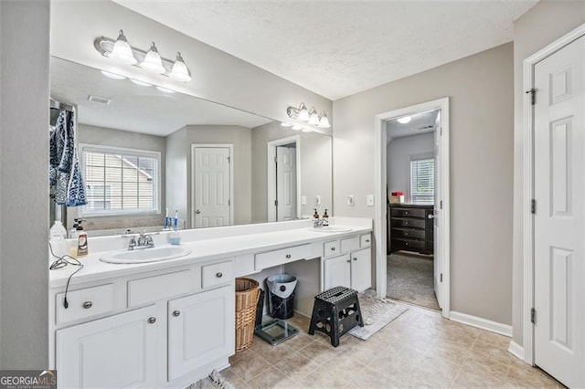 bathroom with vanity, plenty of natural light, a tub, and a textured ceiling