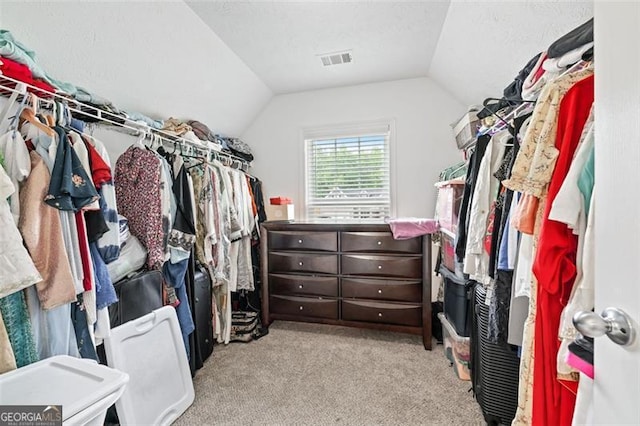 walk in closet with light colored carpet and lofted ceiling