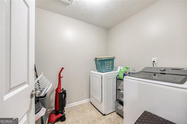 clothes washing area featuring a textured ceiling and washer and clothes dryer