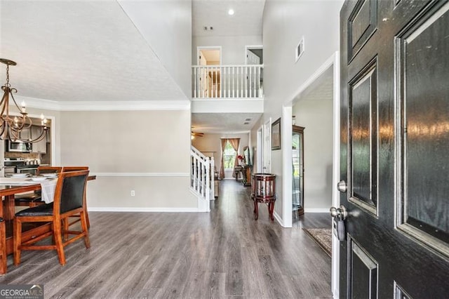 entryway featuring an inviting chandelier, dark wood-type flooring, and ornamental molding