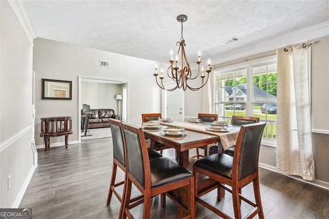 dining room featuring crown molding, dark hardwood / wood-style flooring, an inviting chandelier, and a textured ceiling