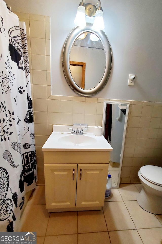 bathroom with toilet, tile walls, vanity, curtained shower, and tile patterned flooring