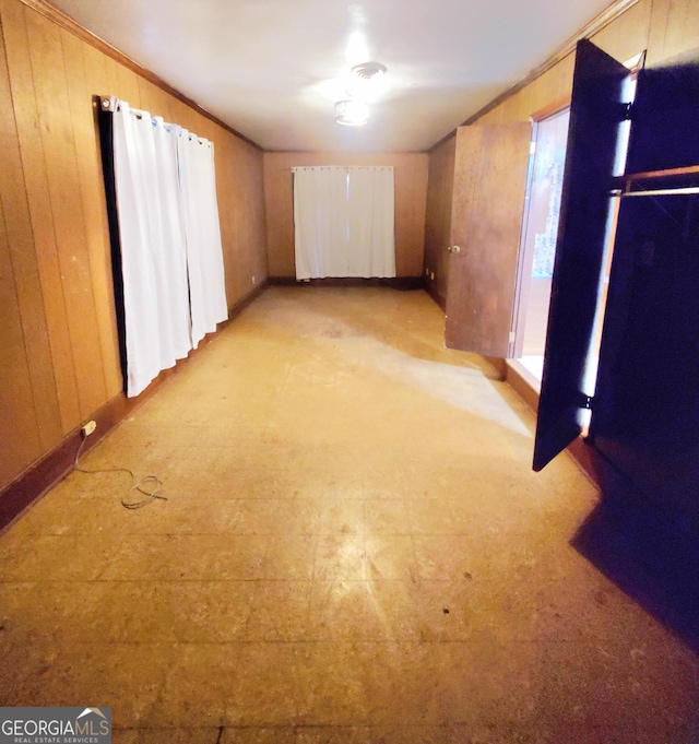 basement featuring light carpet, crown molding, and wood walls