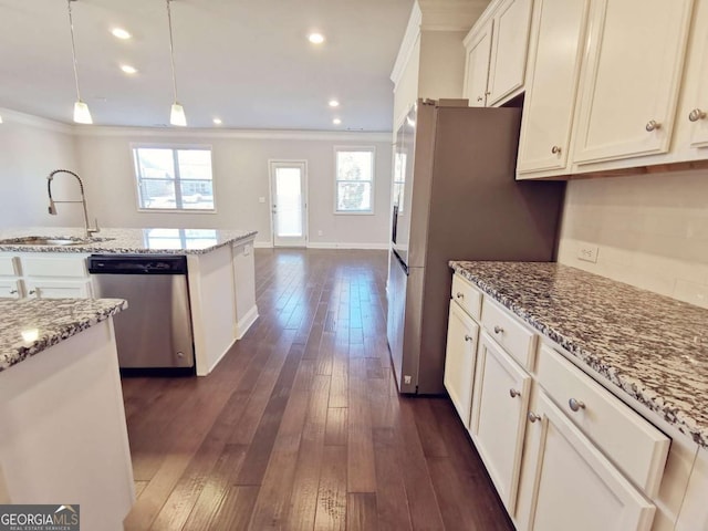 kitchen with pendant lighting, appliances with stainless steel finishes, sink, and light stone counters