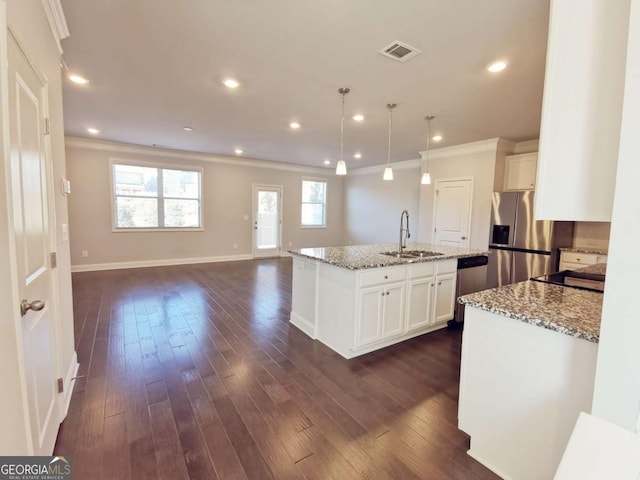 kitchen with sink, light stone counters, hanging light fixtures, a kitchen island with sink, and white cabinets