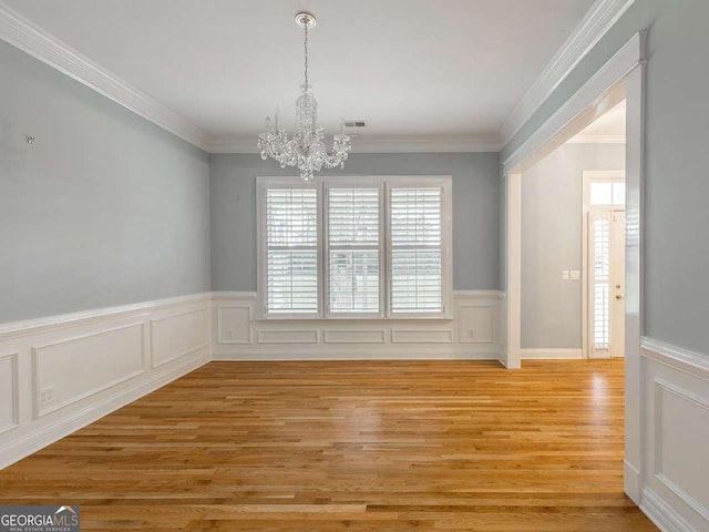 unfurnished dining area featuring crown molding, a chandelier, and light hardwood / wood-style flooring