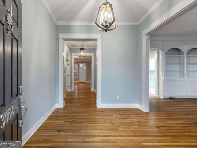 interior space featuring an inviting chandelier, ornamental molding, and wood-type flooring