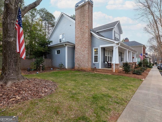 view of side of home featuring covered porch and a lawn