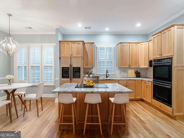 kitchen with light brown cabinetry, a center island, sink, and black appliances