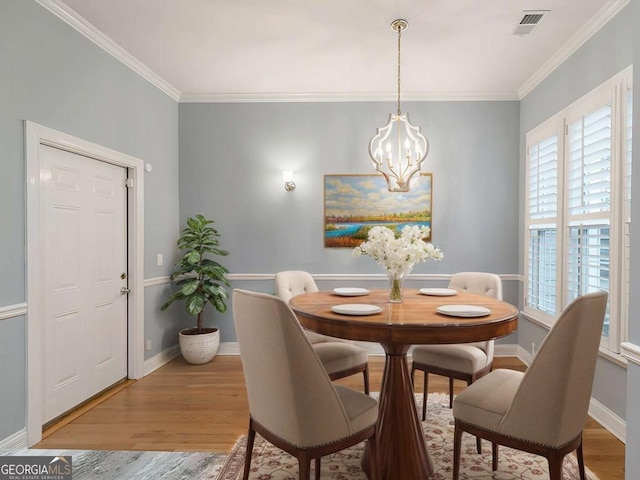 dining area with ornamental molding, a healthy amount of sunlight, hardwood / wood-style floors, and a chandelier