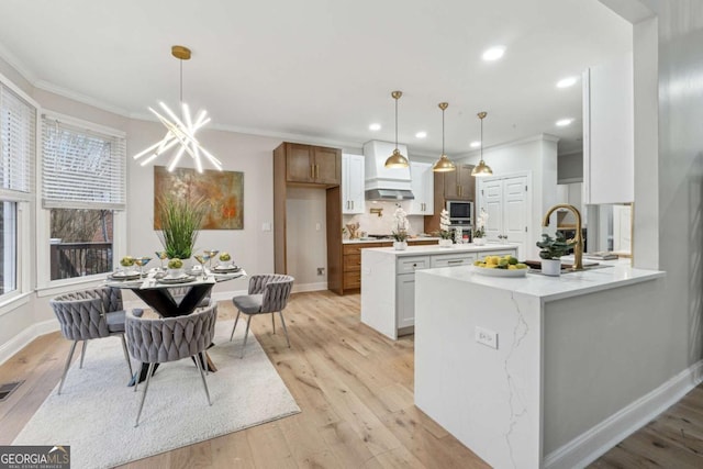 kitchen featuring hanging light fixtures, built in microwave, white cabinets, and light hardwood / wood-style flooring