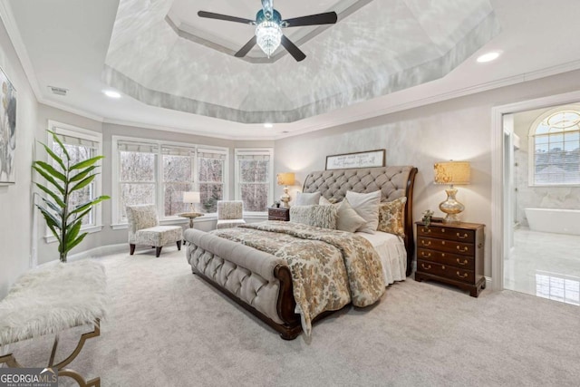 bedroom with crown molding, ceiling fan, connected bathroom, a tray ceiling, and light colored carpet