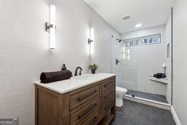 bathroom with vanity, toilet, and tiled shower