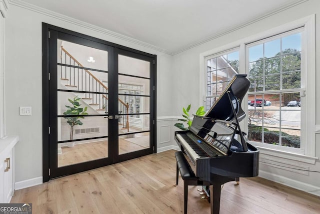 miscellaneous room featuring crown molding, a healthy amount of sunlight, french doors, and light wood-type flooring