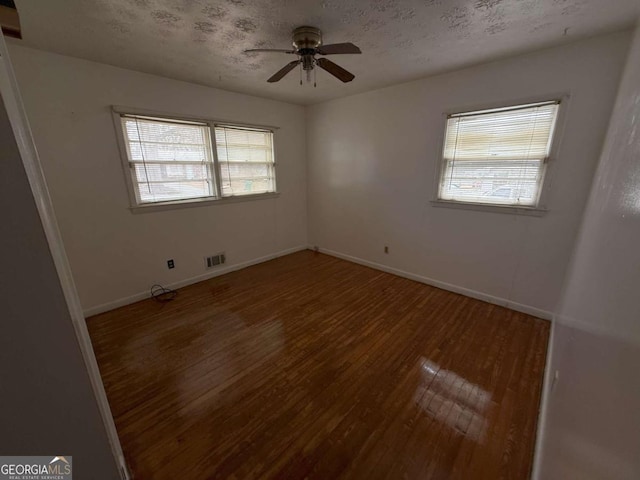 unfurnished room featuring ceiling fan, dark hardwood / wood-style floors, and a textured ceiling