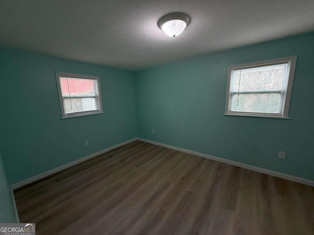 empty room featuring dark wood-type flooring and a textured ceiling