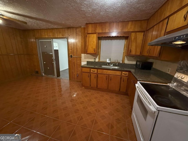 kitchen featuring wood walls, sink, electric range, ceiling fan, and a textured ceiling