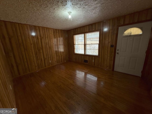 entrance foyer with hardwood / wood-style flooring, a textured ceiling, and wood walls