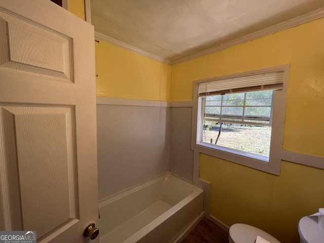 bathroom with a bathtub, ornamental molding, and toilet