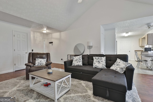 living room with hardwood / wood-style flooring, ceiling fan, lofted ceiling, and a textured ceiling