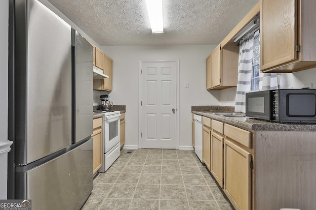 kitchen featuring light brown cabinetry, white appliances, and a textured ceiling