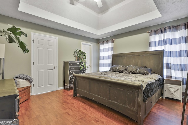 bedroom featuring hardwood / wood-style flooring, ceiling fan, and a tray ceiling