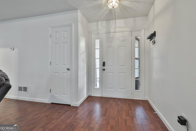 foyer entrance featuring dark wood-type flooring and a textured ceiling