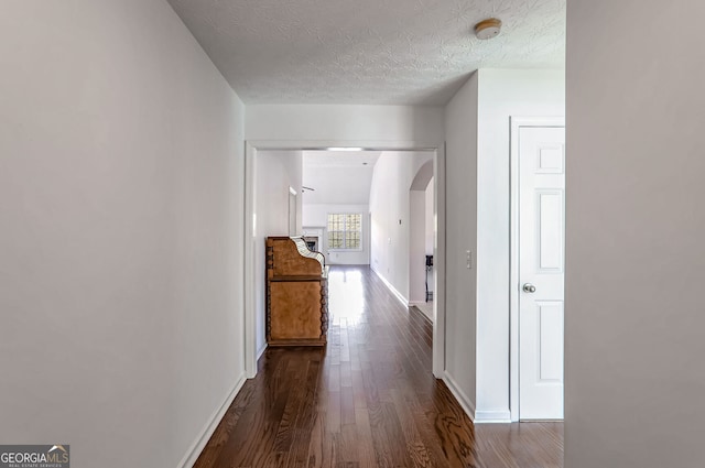 corridor with dark hardwood / wood-style floors and a textured ceiling