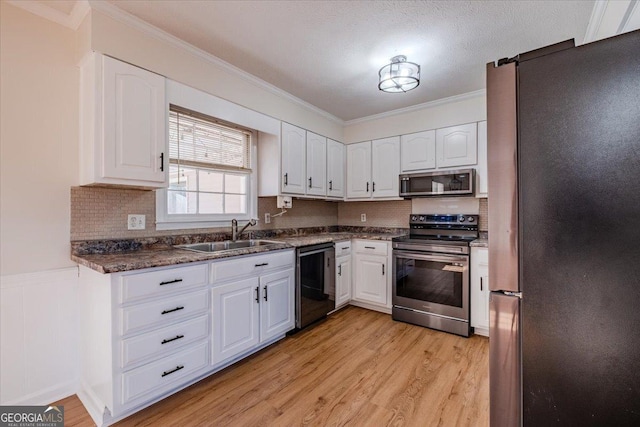 kitchen featuring sink, white cabinetry, light hardwood / wood-style flooring, a textured ceiling, and appliances with stainless steel finishes