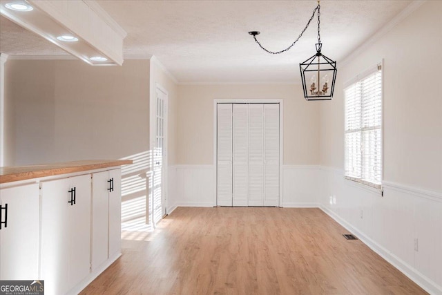 unfurnished dining area with crown molding and light hardwood / wood-style floors