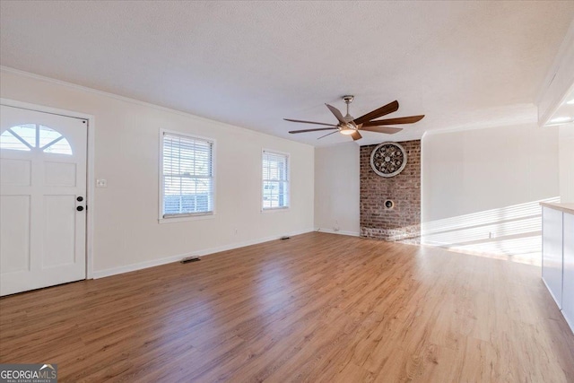 foyer with a textured ceiling, light hardwood / wood-style flooring, ornamental molding, and ceiling fan