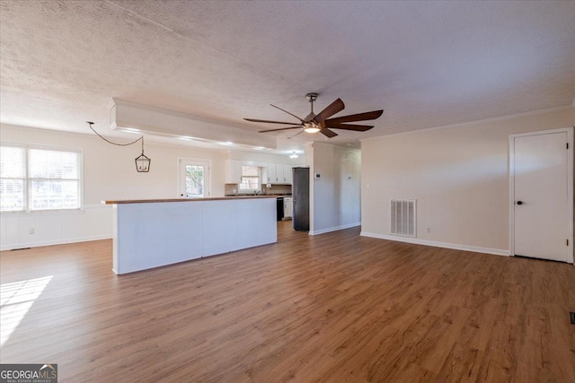 unfurnished living room with hardwood / wood-style flooring, a wealth of natural light, a textured ceiling, and ceiling fan