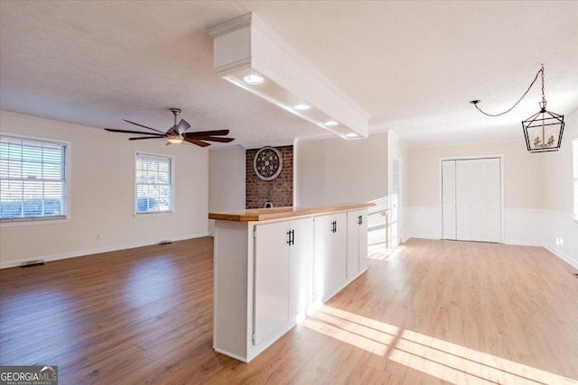 kitchen with pendant lighting, white cabinets, ceiling fan, a textured ceiling, and light hardwood / wood-style flooring