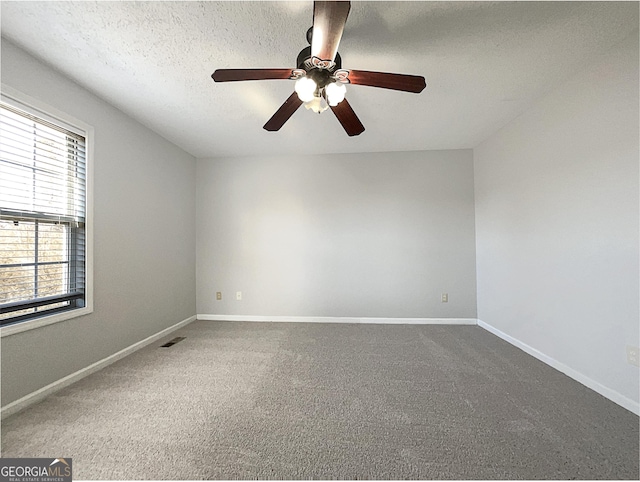 carpeted spare room featuring ceiling fan and a textured ceiling