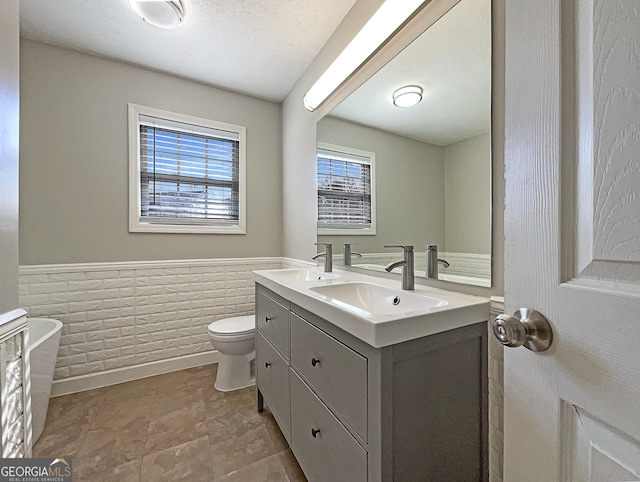 bathroom featuring vanity, toilet, tile walls, and a textured ceiling