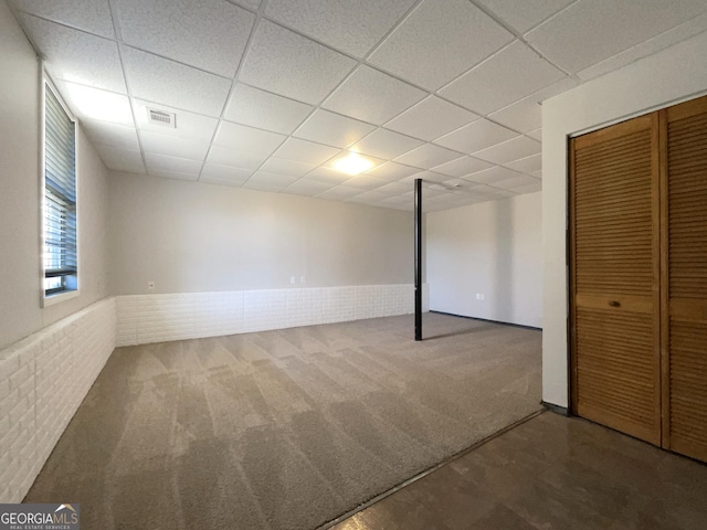 basement with brick wall, carpet floors, and a drop ceiling